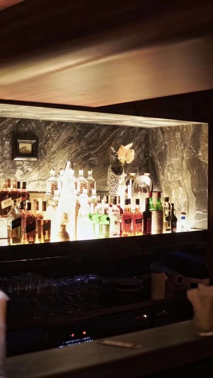 Balcão do bar com parede de pedra iluminada e garrafas