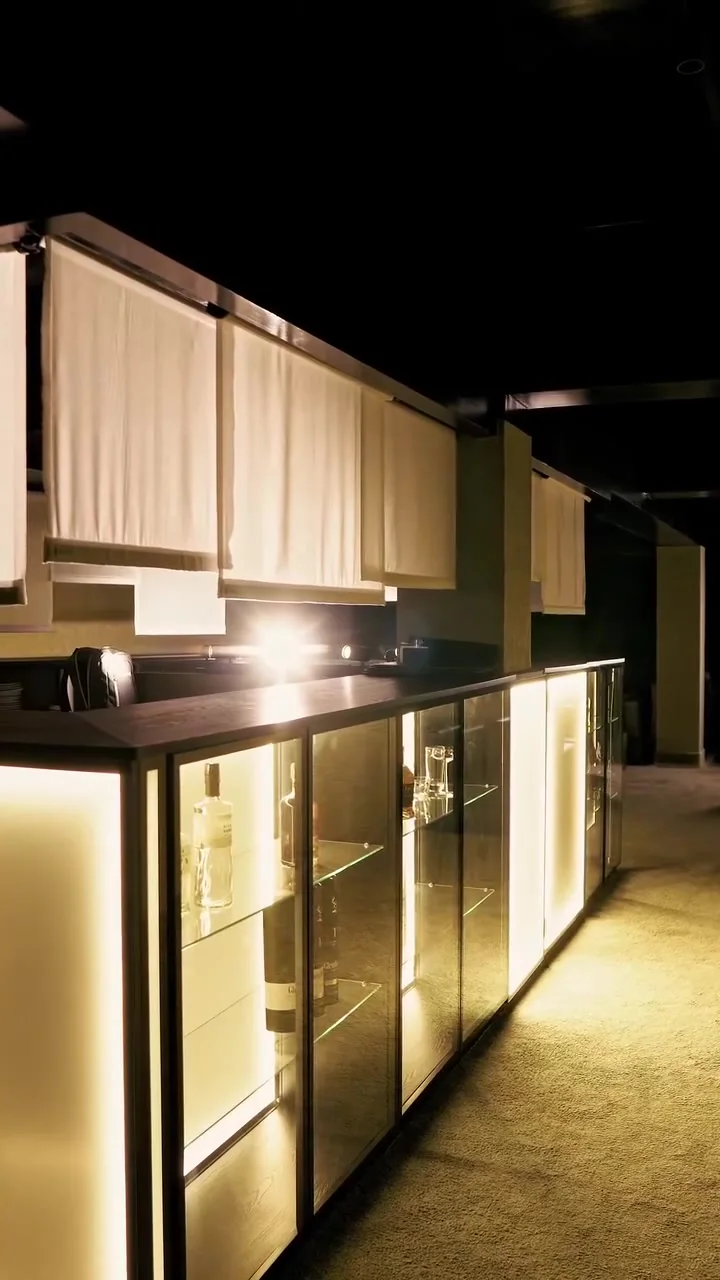 Speakeasy, CASACOR SP 2026: balcão iluminado, vitrines de vidro e persianas suspensas